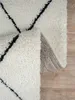 A close-up view of a shaggy rug with a diamond pattern, showing the texture and underside. Produktbild-Vorschau