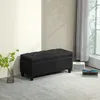 A black tufted storage bench is placed on a light gray carpet in a room with a white wall and a window with sheer curtains. Náhled obrázku produktu