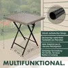 A square outdoor table with a woven top and folding metal legs, shown on a wooden deck with a blurred background of greenery and flowers. Text overlays describe its features and dimensions. Produktbild-Vorschau