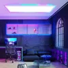 A modern gaming or office room with a desk, chair, couch, and shelves, illuminated by colorful LED lighting. Produktbild-Vorschau