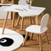 A white children's table and two chairs are set up on a rug, with drawing supplies on the table. Náhled obrázku produktu