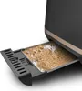 A close-up view of a toaster's crumb tray, which is pulled out and filled with crumbs. Voir les images du produit