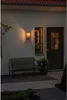 An outdoor wall lamp illuminates a bench and a doorway at dusk. Produktbild-Vorschau