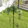 A bird feeder station with multiple feeders is set up in a grassy backyard with a white fence and stone steps in the background. Voir les images du produit