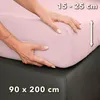 Hands are shown adjusting a pink fitted sheet on a mattress. Produktbild-Vorschau