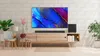 A living room setup with a TV, soundbar, subwoofer, and furniture. Produktbild-Vorschau