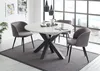 A dining room scene with a round extendable table and chairs, set against a large window with a city view. Produktbild-Vorschau