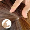 A close-up of a person's fingers holding clear elastic hair ties around strands of brown and auburn hair. Anteprima dell’immagine prodotto