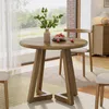 A round wooden dining table with chairs in a well-lit room with a large window. Anteprima dell’immagine prodotto