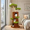 A cat tree designed to look like a tree trunk with green platforms and openings, placed in a bedroom setting next to a bed and a window. Produktbild-Vorschau