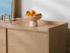 A close-up shot of a wooden dresser with a bowl of oranges on top, next to a mirror and candle holders. Náhľad obrázku produktu