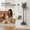 A woman is petting her dog next to a wall-mounted vacuum cleaner and its charging accessories. Náhled obrázku produktu