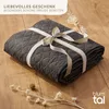 A folded dark gray blanket tied with a ribbon, placed on a wooden surface with dried flowers. Náhled obrázku produktu