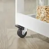 A close-up view of the caster wheel and locking mechanism of a white kitchen cart. Produktbild-Vorschau