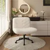 A fluffy ivory office chair is placed on a round rug in front of a vanity table with a lighted mirror and various cosmetic items.