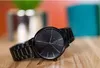 A black Armani Exchange watch is displayed on a wooden surface with a blurred background of colorful objects. Anteprima dell’immagine prodotto