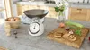 A kitchen counter with a retro-style analog scale, eggs in a bowl, a boiled egg in a cup, and ingredients for cooking on a cutting board. Voir les images du produit