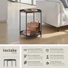 A round, two-tiered side table with a briefcase and books on it, next to a sofa. Produktbild-Vorschau