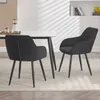 Two black dining chairs are placed around a white dining table in a well-lit room with a shelf in the background. Produktbild-Vorschau