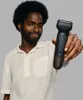 A man is holding a hair trimmer and smiling at the camera. Produktbild-Vorschau