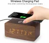 A hand places a smartphone on a wooden digital alarm clock with wireless charging capabilities. Anteprima dell’immagine prodotto