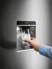 A hand is holding a glass filled with ice under an ice dispenser on a refrigerator. Náhled obrázku produktu