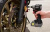 A hand holding a cordless impact wrench is shown next to a motorcycle wheel and brake disc. Produktbild-Vorschau