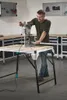 A man is using a drill press on a workbench in a workshop. Náhľad obrázku produktu