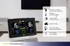 A digital weather station is displayed on a table in a modern living room setting, with a large TV and furniture in the background. A transparent overlay highlights the product's features. Produktbild-Vorschau
