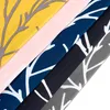 A close-up view of several folded fabric swatches with a repeating tree branch pattern in different colors. Produktbild-Vorschau