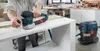 A person is using a Bosch sander connected to a Bosch vacuum cleaner in a workshop. Náhled obrázku produktu