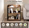 A 3-tier storage rack with books and decorative items on a wooden floor next to a sofa. Podgląd zdjęcia produktu