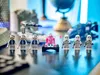 LEGO Star Wars figures and vehicles arranged on a reflective surface, with a blurred background of a globe and other objects. Náhled obrázku produktu