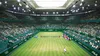 A tennis match taking place in a large, green-themed stadium filled with spectators. Produktbild-Vorschau