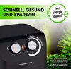 A close-up of a black air fryer with control dials, set against a blurred background of green foliage and a promotional graphic. Produktbild-Vorschau