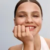 A woman's hand with a ring is held to her face as she smiles. Anteprima dell’immagine prodotto