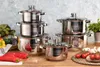 A set of stainless steel pots and pans are arranged on a wooden table, with some vegetables and tomatoes in the foreground. Náhled obrázku produktu