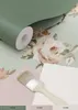 A roll of mint green textured wallpaper with a floral pattern is shown, alongside swatches of pink and cream paper and a paintbrush. Produktbild-Vorschau