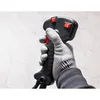 A gloved hand holding the handle of a tool, possibly a string trimmer or similar garden equipment, showing the controls and grip. Produktbild-Vorschau