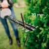 A person is using a hedge trimmer to cut a branch. Voir les images du produit