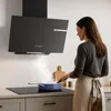 A woman is cooking on a stovetop under a modern black range hood. Voir les images du produit
