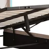 A close-up view of the underside of a bed frame, showing the hydraulic lift mechanism and wooden slats. Produktbild-Vorschau
