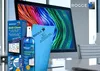 A computer screen with a colorful display, a cleaning spray bottle, a cleaning cloth, and a box of cleaning products are arranged on a desk. Produktbild-Vorschau
