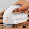 A hand is holding a white fabric shaver over a brown blanket with paw prints. Podgląd zdjęcia produktu