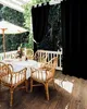 A patio dining set with chairs and a table on a wooden deck, partially covered by a white awning and black outdoor curtains. Náhľad obrázku produktu