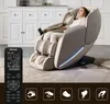 A woman is relaxing in a beige massage chair in a well-lit room with a white cabinet in the background. A remote control for the chair is in the foreground. Produktbild-Vorschau