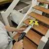 A person is cleaning the wooden steps of a staircase with a yellow and gray floor cleaner. Produktbild-Vorschau