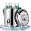 A stainless steel insulated beverage dispenser filled with ice and bottles of colorful drinks, with the lid open and ice cubes scattered around the base. Voir les images du produit