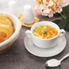 A bowl of chicken noodle soup with bread rolls and flowers in the background. Podgląd zdjęcia produktu