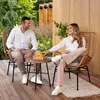 A couple sitting on a wooden deck in a garden setting, enjoying a conversation over a small table with oranges. Náhled obrázku produktu